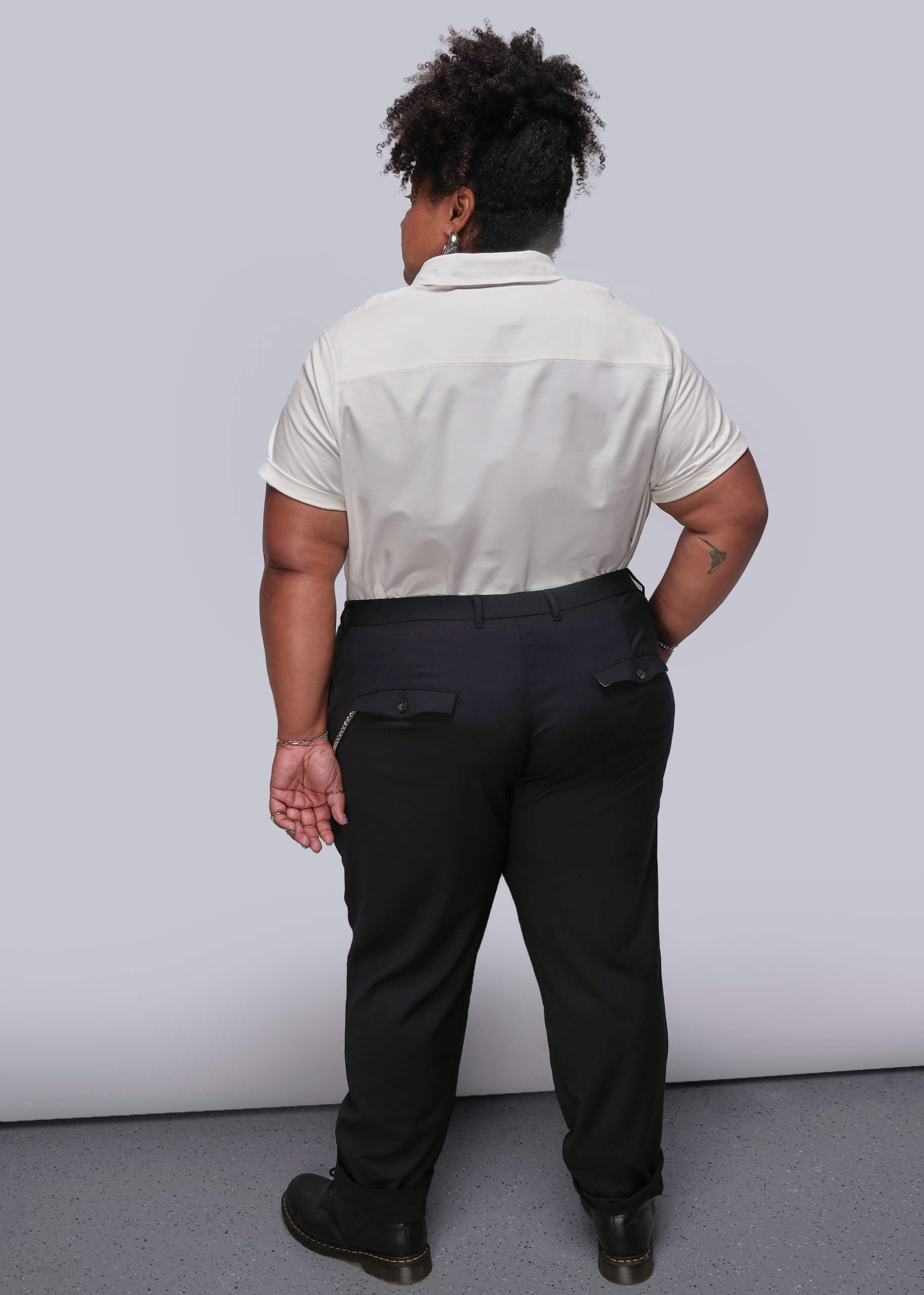 1X=Person wearing a white shirt and black pants against a plain background
