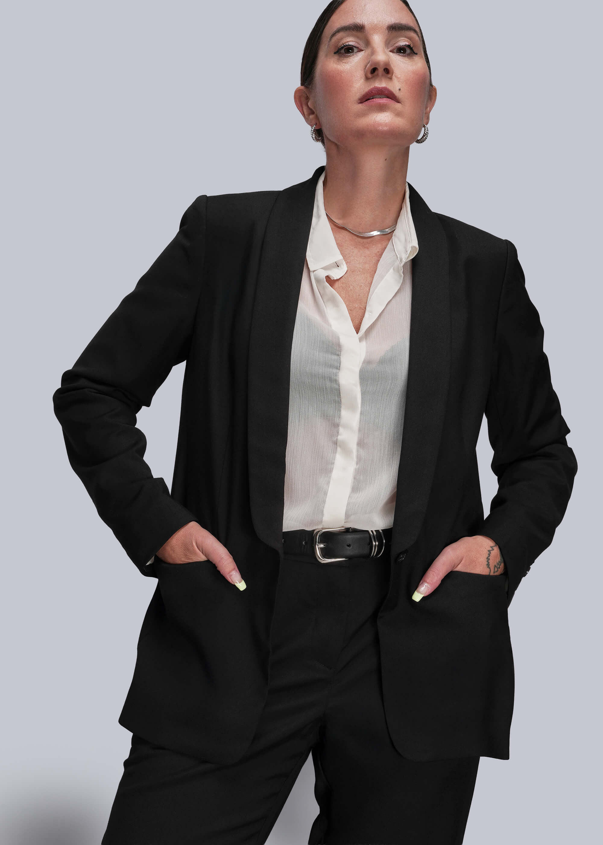 Person wearing a black suit with a white shirt on a light gray background