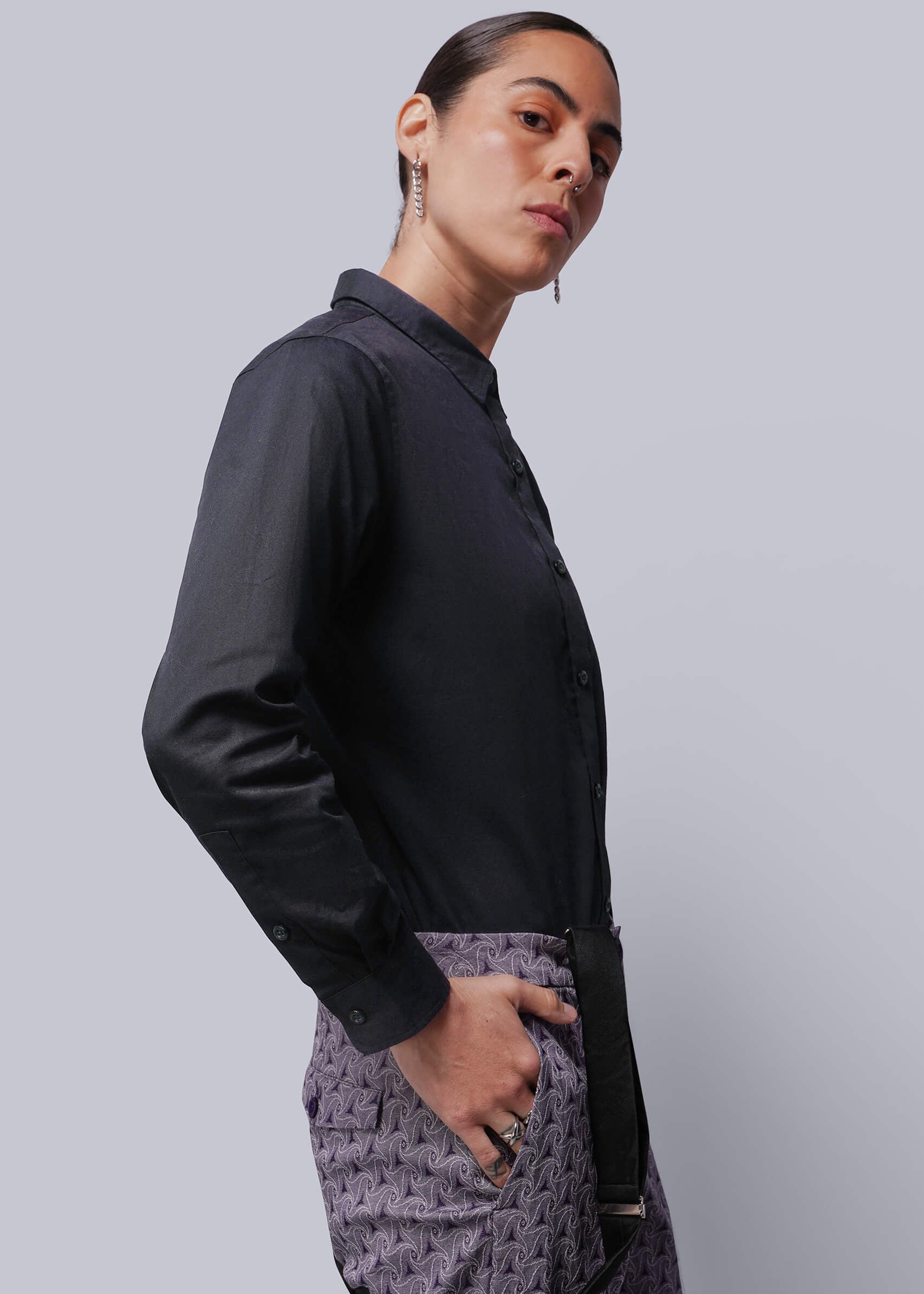 S=Person wearing a black shirt and patterned pants against a gray background