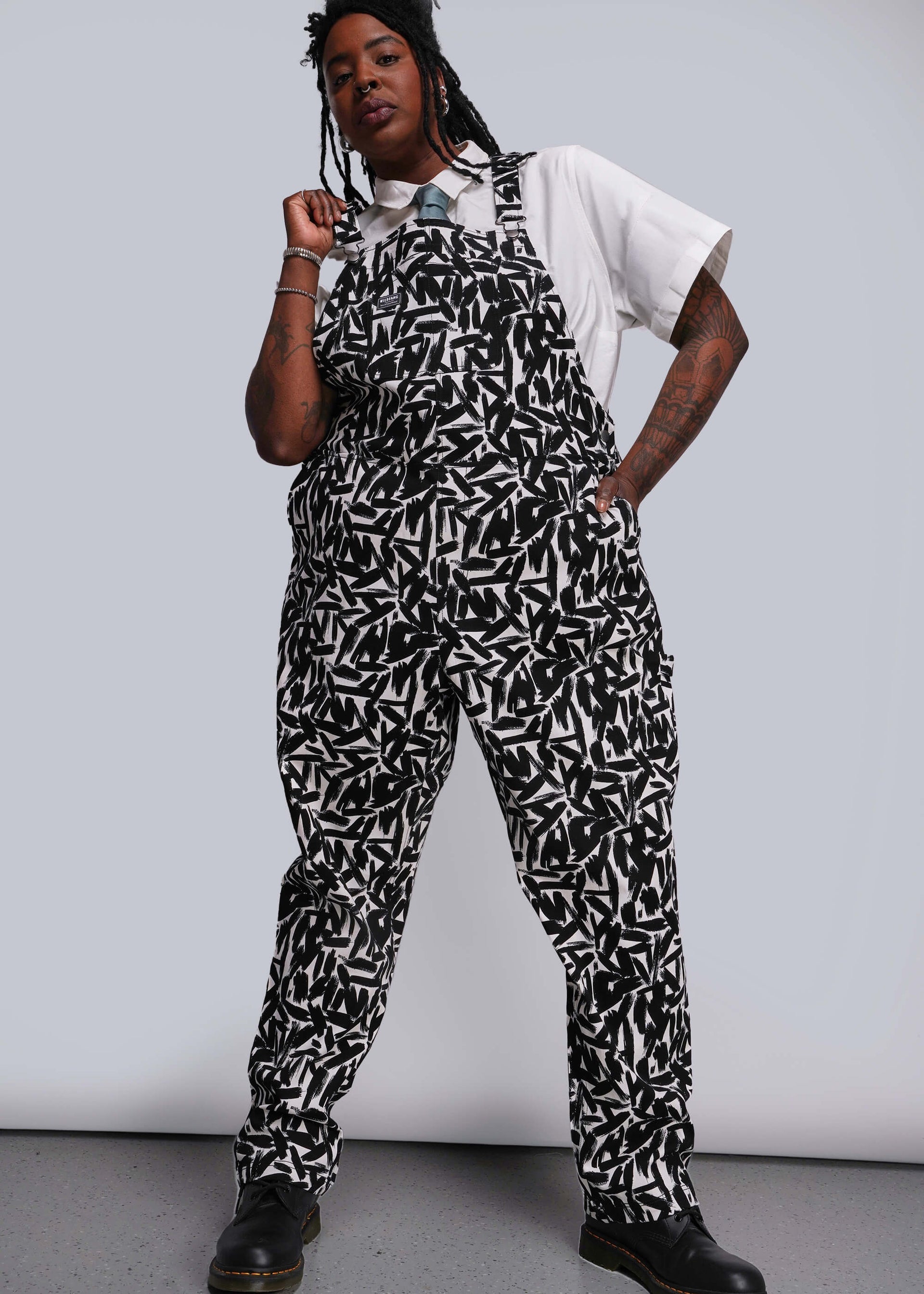 1X=Person wearing a black and white patterned jumpsuit against a plain background