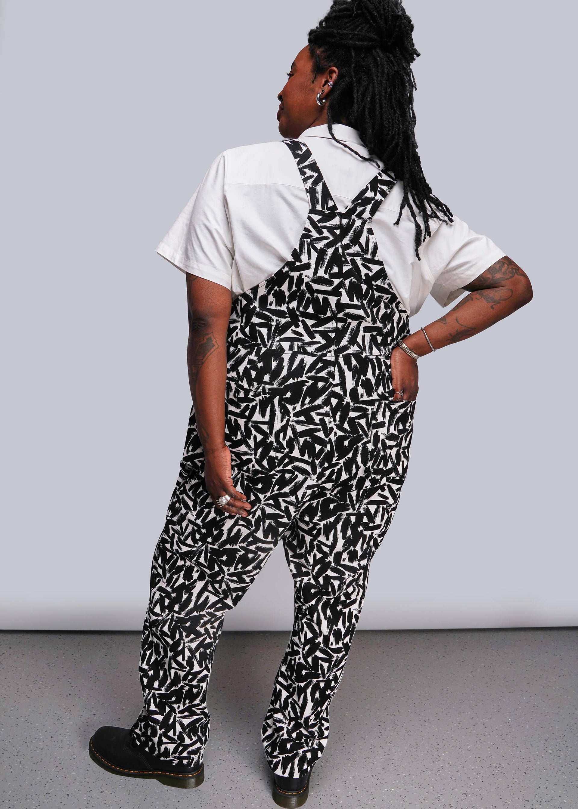 1X=Person wearing a black and white patterned overalls with a plain background