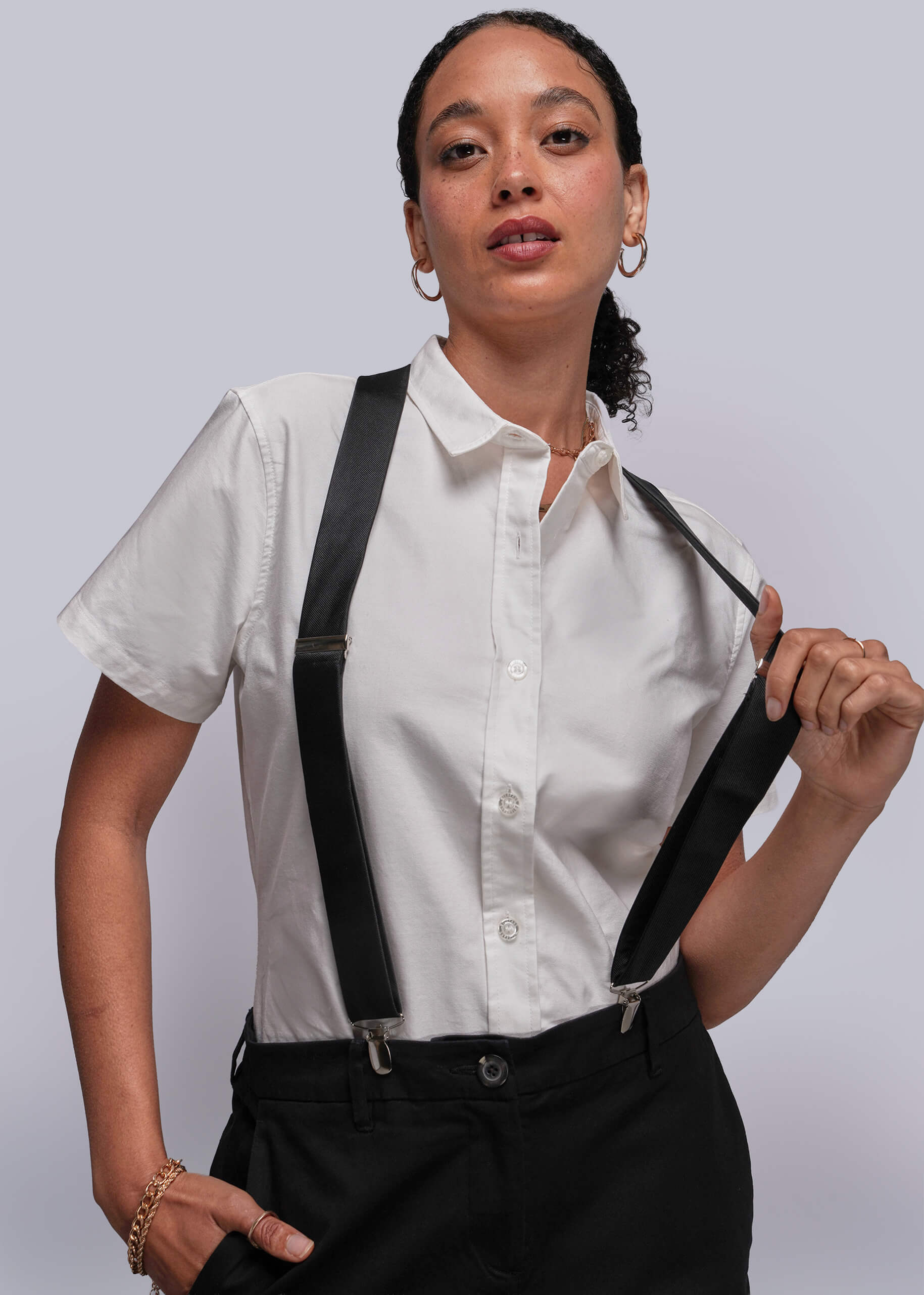 Person wearing a white shirt with black suspenders against a plain background