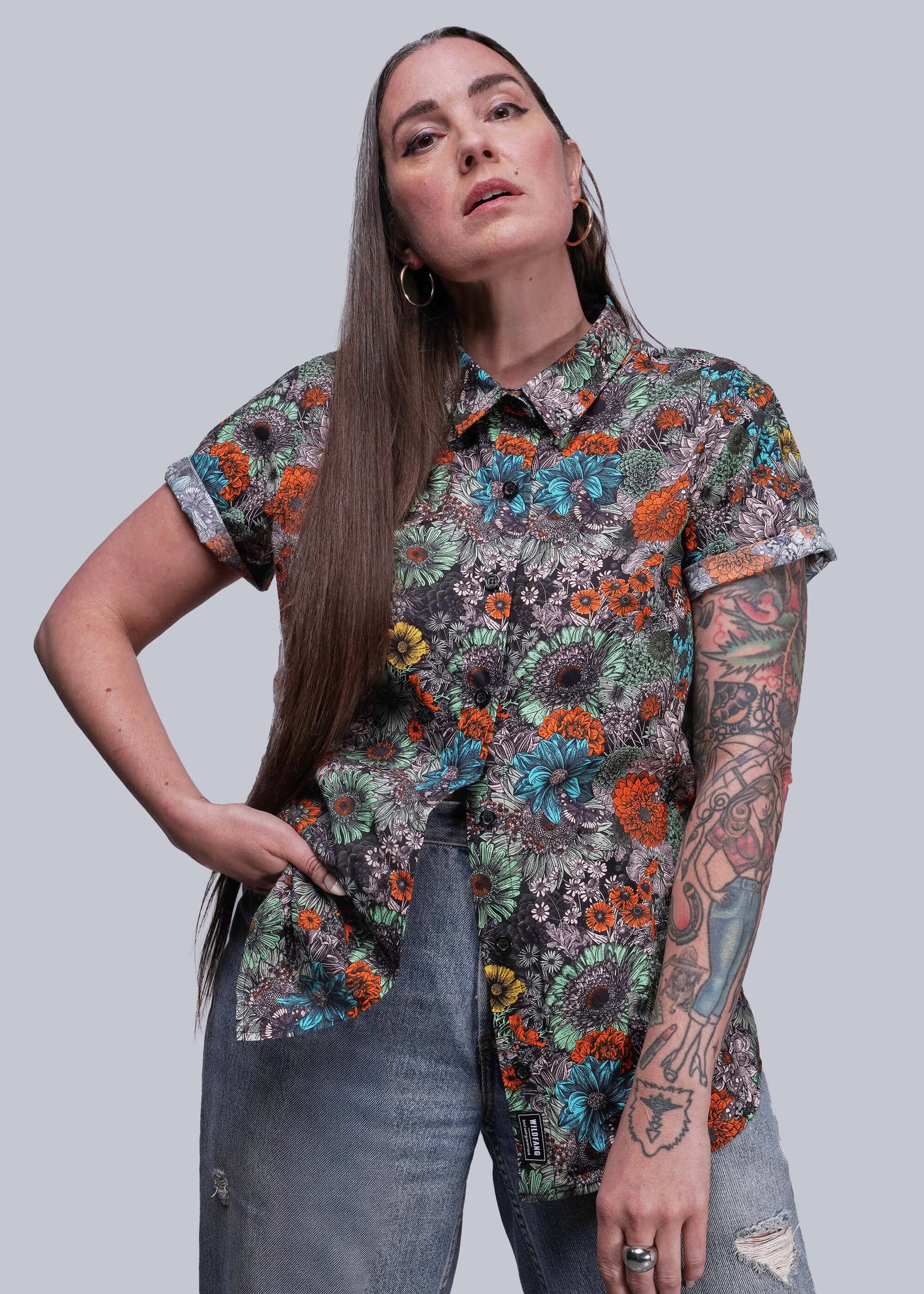 S=Woman wearing a colorful floral shirt against a plain background