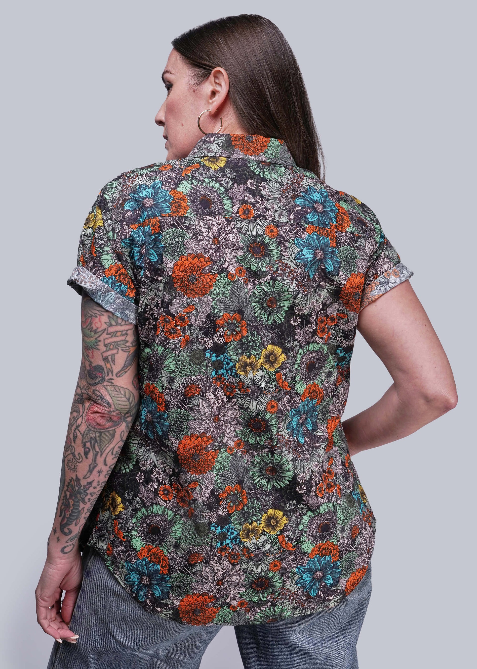S=Person wearing a colorful floral patterned shirt on a plain background