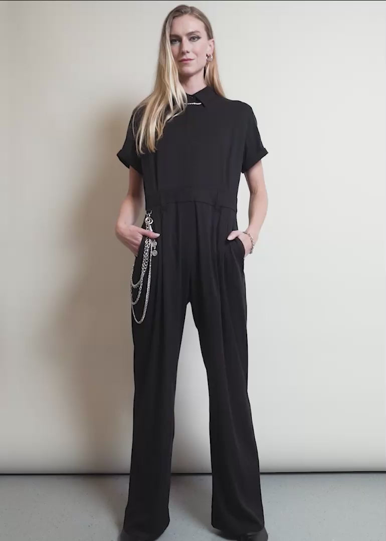 A model wearing The Debbie Harry x Wildfang Jumpsuit shows the fit and features of the product including pockets and stretch