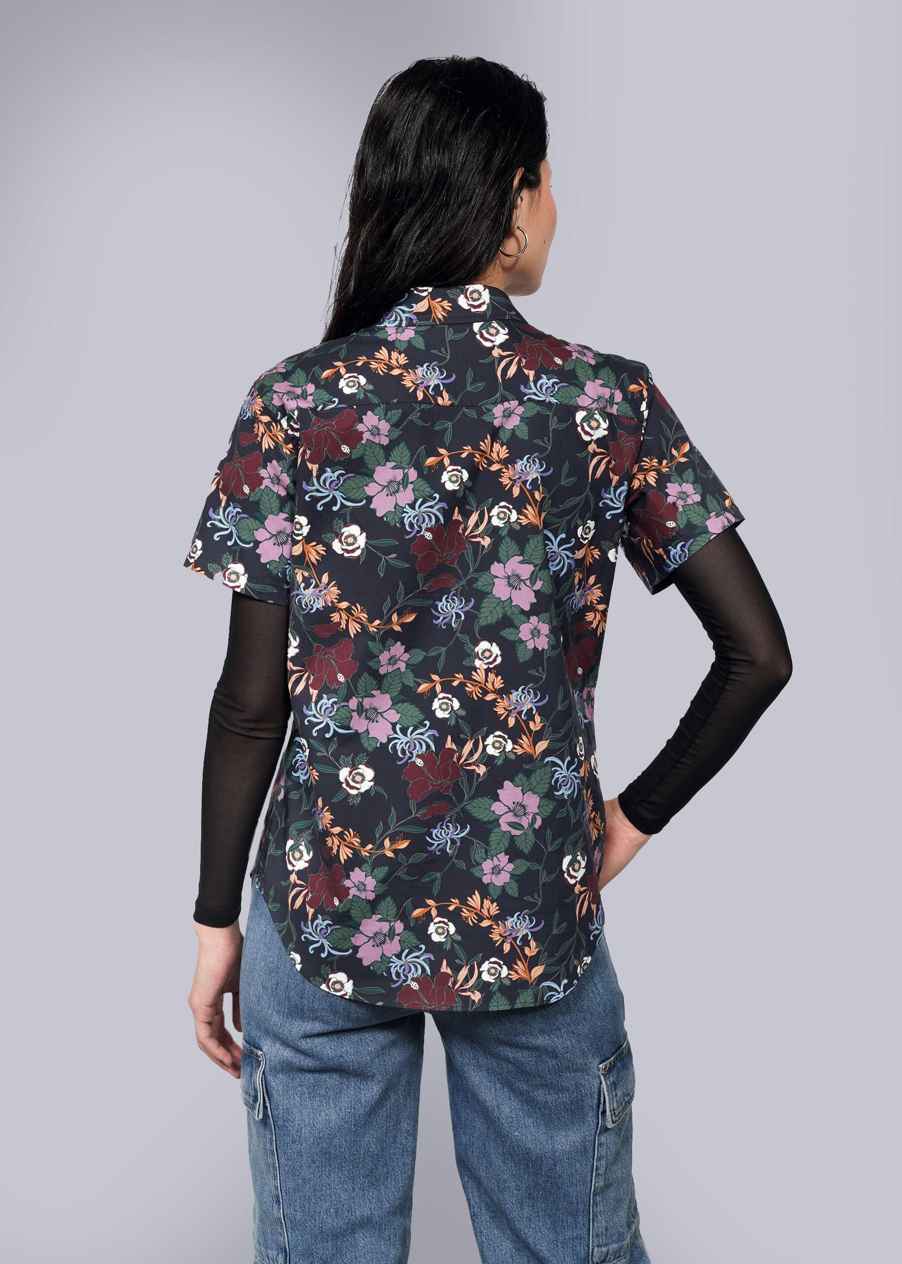 S=A person with long dark hair, seen from behind, wears The Essential Button Up over a black long-sleeve top and blue jeans against a plain white background.